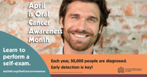 A smiling person stands in front of a brick wall next to a public health poster that reads “April is Oral Cancer Awareness Month.” The poster encourages learning how to perform a self‑exam and highlights that 50,000 people are diagnosed each year, emphasizing early detection.