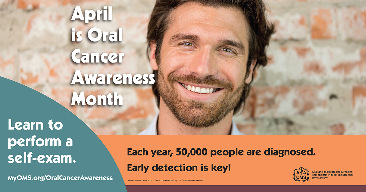 A smiling person stands in front of a brick wall next to a public health poster that reads “April is Oral Cancer Awareness Month.” The poster encourages learning how to perform a self‑exam and highlights that 50,000 people are diagnosed each year, emphasizing early detection.