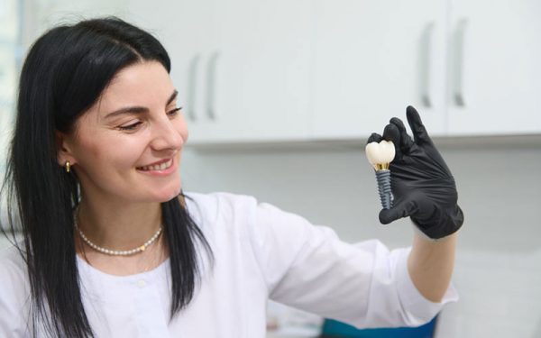 oung woman holding dental implant mockup, artificial tooth roots into jaw canal. dental treatment concept.