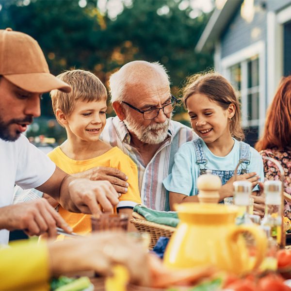 grandfather and his family gathered around a backyard table for dinner